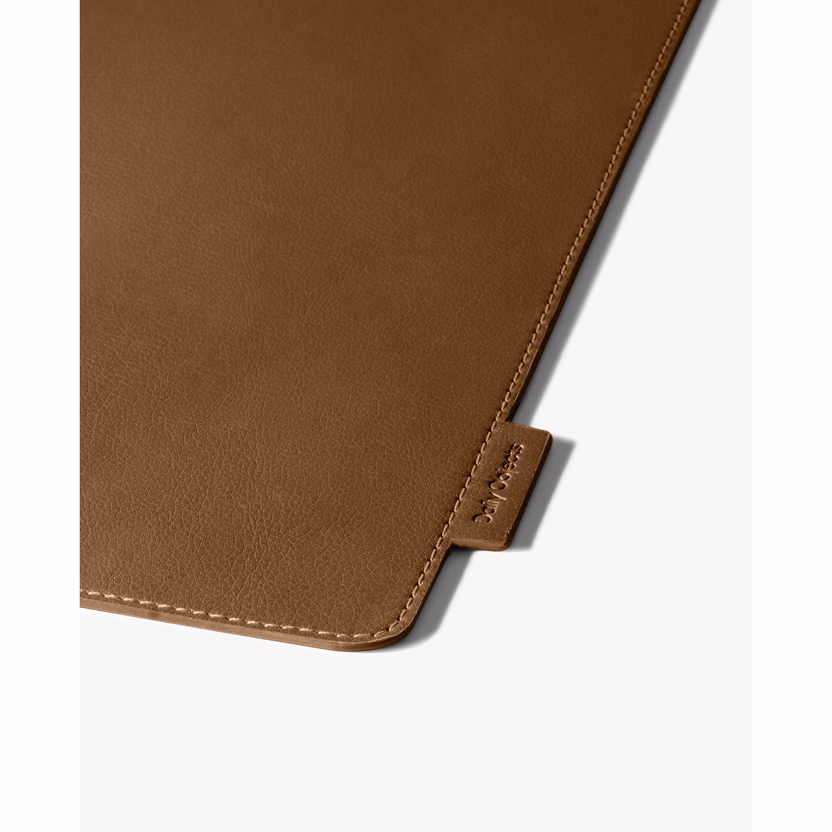 Tan-Brown Snap On Organiser Desk Mat with Cable Holder + Phone Mount + Apple Watch Charging Stand in Tan – Close-up of textured surface with stitched edge and tag | KlippiK
