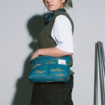 Female model wearing blue alligator crossbody bag with olive vest | KlippiK Kuwait