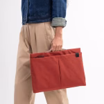 Female model holding coral red Pivot laptop sleeve open | KlippiK Kuwait