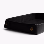 Black leather DailyObjects valet tray angled view showing brass snap button and stitch detail — Middle East