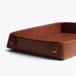 Brown leather DailyObjects valet tray angled view showing brass snap button and stitch detail — UAE