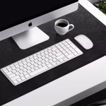 Black leather desk mat with iMac Apple keyboard Magic Mouse and coffee — stylish workspace desk accessories Middle East