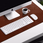 Brown leather desk mat with iMac Apple keyboard Magic Mouse and coffee mug — stylish workspace desk accessories UAE