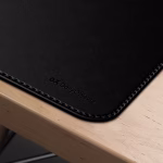 Corner detail of black leather DailyObjects desk mat with stitched edges on wooden desk — desk accessories Middle East