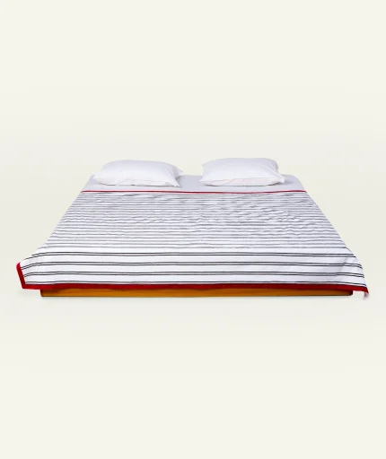 Cloudy Black with Candy Red Muted Layers Dohar shown made up on a low wooden platform bed with two matching pillows