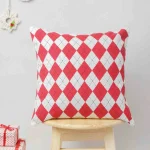 Cross Stitch Cushion Cover by Yellow Dwelling, styled on a light wood stool against a pale wall