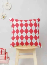 Cross Stitch Cushion Cover by Yellow Dwelling, styled on a light wood stool against a pale wall