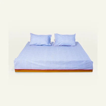 Dreamy Blue with Candy Red Silent Stripes Flat Bedsheet shown made up on a low wooden platform bed with two matching pillows
