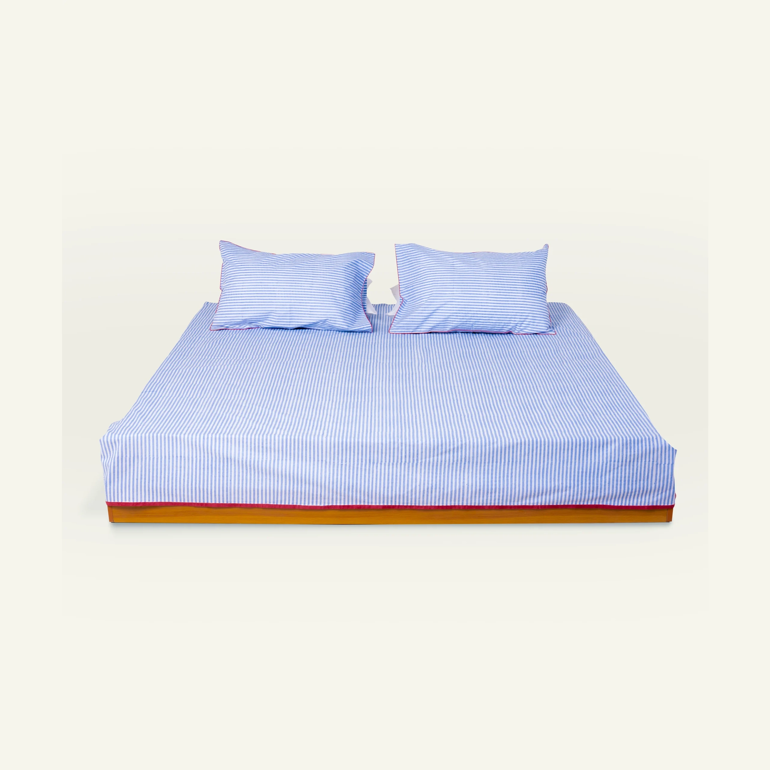Pale blue Red Silent stripes 1 copy Dreamy Blue with Candy Red Silent Stripes Flat Bedsheet shown made up on a low wooden platform bed with two matching pillows