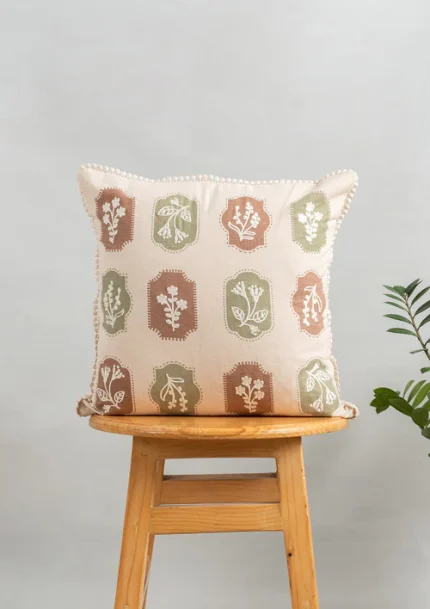 Stamps Embroidered Floral Motif 100% Cotton Cushion Cover for Sofa - Green and Rust by Yellow Dwelling, styled on a light wood stool against a pale wall
