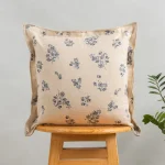 Whisper Printed Linen Flower Motif Cushion Cover for Sofa - Blue by Yellow Dwelling, styled on a light wood stool against a pale wall