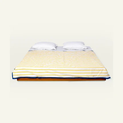 Mellow Yellow with Misty Blue Muted Layers Dohar shown made up on a low wooden platform bed with two matching pillows