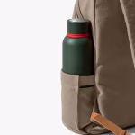 Side water bottle pocket of beige daypack holding green metal bottle | KlippiK Worldwide