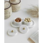 White marble tray holding two lidded trinket bowls filled with nuts, on a light table