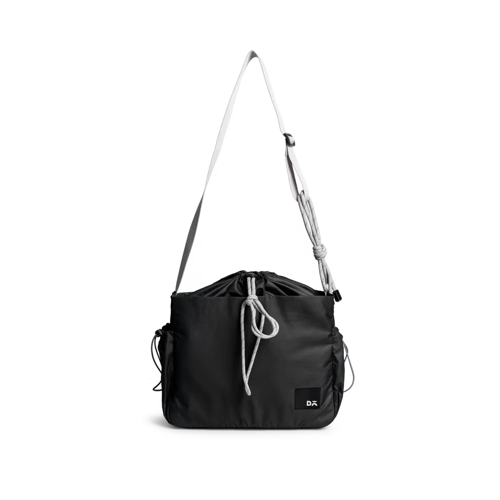 Carbon-Black-Pass-Satchel-Bag Carbon Black Pass Satchel Bag with a drawstring top and wide crossbody strap, shown on white