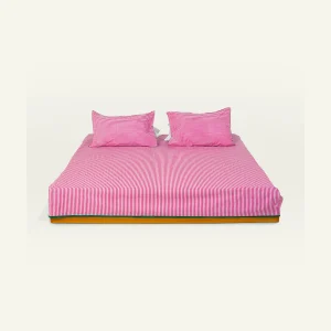 Berry Pink with Pearl Green Silent Stripes Flat Bedsheet shown made up on a low wooden platform bed with two matching pillows