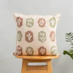 Stamps Embroidered Floral Motif 100% Cotton Cushion Cover for Sofa - Green and Rust by Yellow Dwelling, styled on a light wood stool against a pale wall