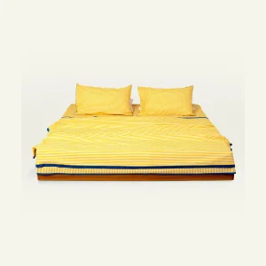 Mellow Yellow with Misty Blue Silent Stripes bed linen shown made up on a low wooden platform bed with two matching pillows