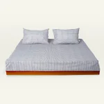 Cloudy Black with Candy Red Pure Stripes Flat Bedsheet shown made up on a low wooden platform bed with two matching pillows