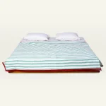Pearl Green with Candy Red Muted Layers Dohar shown made up on a low wooden platform bed with two matching pillows