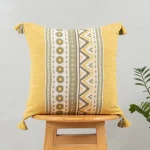 Nadar 100% Cotton Printed Geometric Cushion Cover for Sofa with Tassels – Yellow by Yellow Dwelling, styled on a light wood stool against a pale wall