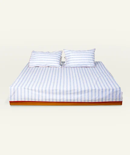 Dreamy Blue with Candy Red Muted Layers Flat Bedsheet shown made up on a low wooden platform bed with two matching pillows