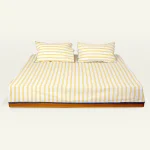 Mellow Yellow with Misty Blue Muted Layers Flat Bedsheet shown made up on a low wooden platform bed with two matching pillows