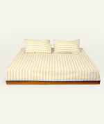 Mellow Yellow with Misty Blue Muted Layers Flat Bedsheet shown made up on a low wooden platform bed with two matching pillows