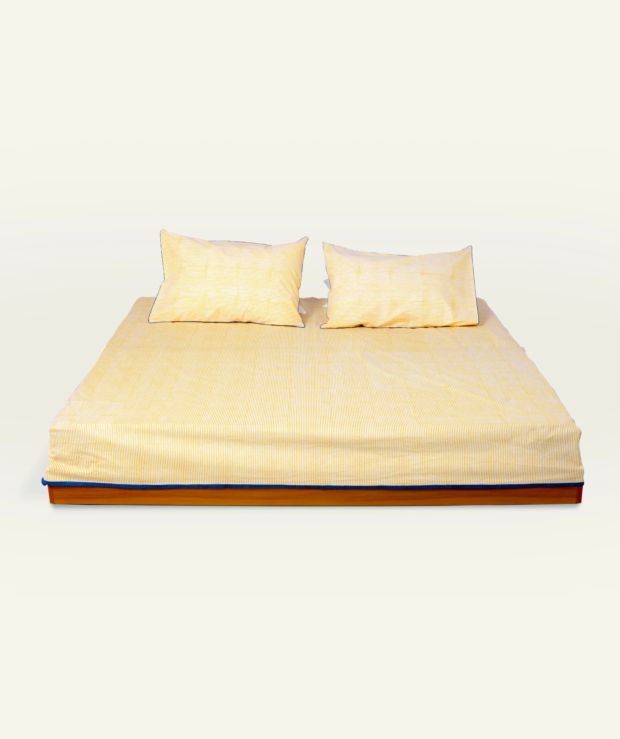 Yellow Indigo Pure stripes 1 copy Mellow Yellow with Misty Blue Pure Stripes Flat Bedsheet shown made up on a low wooden platform bed with two matching pillows