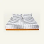 Cloudy Black with Candy Red Muted Layers Flat Bedsheet shown made up on a low wooden platform bed with two matching pillows