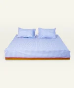Dreamy Blue with Candy Red Silent Stripes Flat Bedsheet shown made up on a low wooden platform bed with two matching pillows