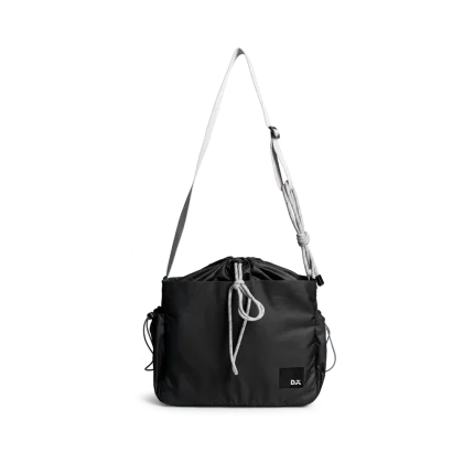 Carbon Black Pass Satchel Bag with a drawstring top and wide crossbody strap, shown on white