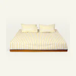 Mellow Yellow with Misty Blue Muted Layers Flat Bedsheet shown made up on a low wooden platform bed with two matching pillows
