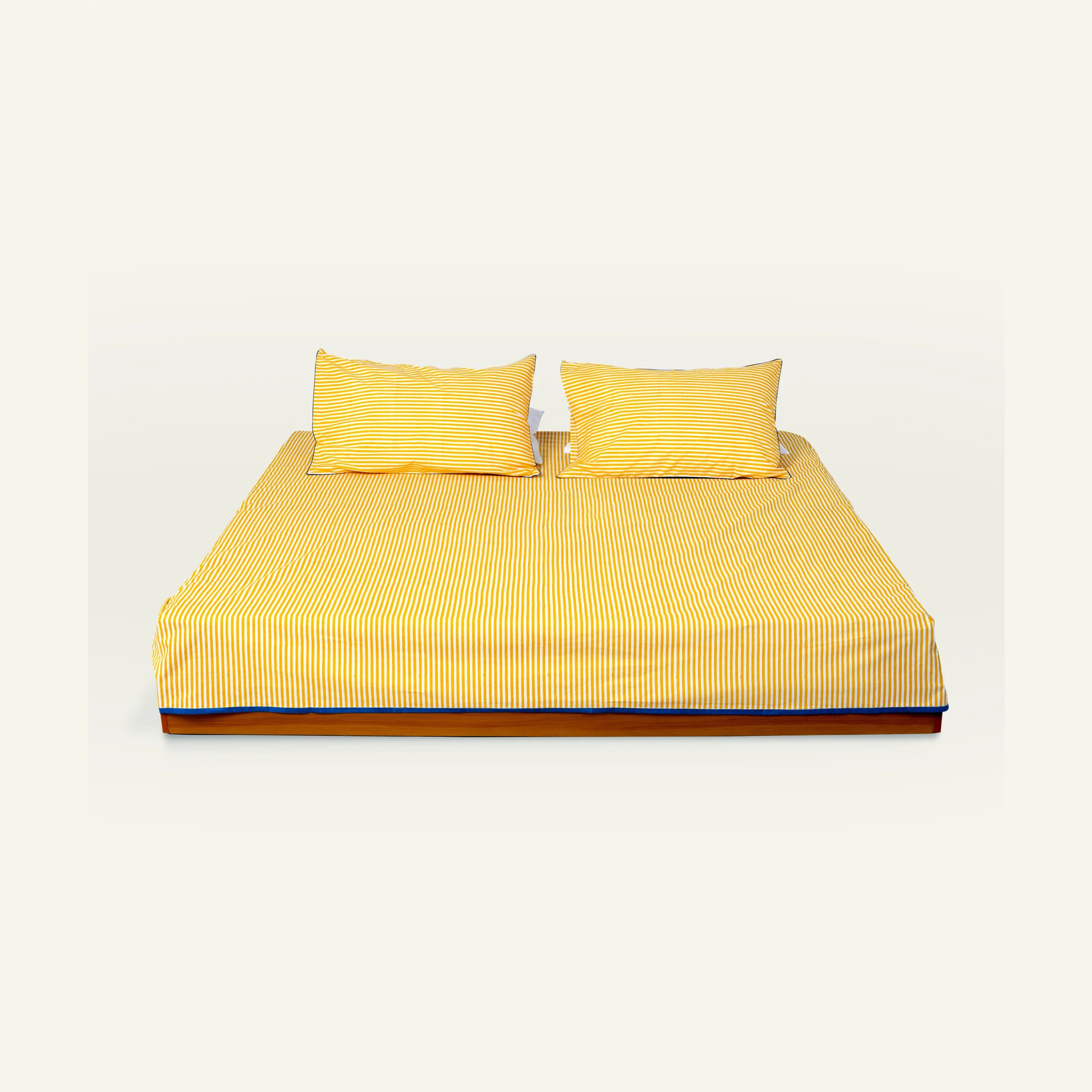 Yellow Indigo Silent stripes 3 copy Mellow Yellow with Misty Blue Silent Stripes Flat Bedsheet shown made up on a low wooden platform bed with two matching pillows